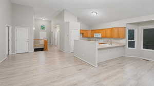 Kitchen featuring light countertops, a peninsula, lofted ceiling, white appliances, and open floor plan