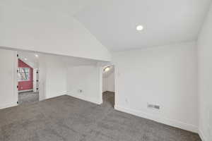 Additional living space featuring lofted ceiling, dark colored carpet, and recessed lighting
