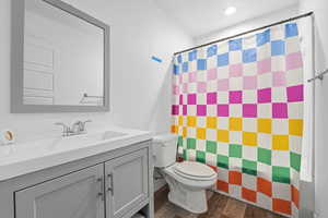 Full bath with vanity, curtained shower, and dark wood-type flooring