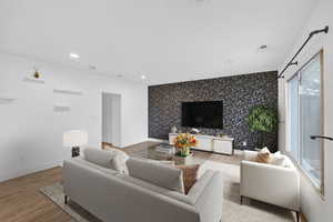 Living room featuring an accent wall, wallpapered walls, light wood-style floors, and recessed lighting