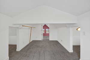 Additional living space with dark carpet and baseboards