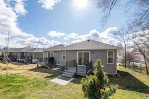 Back of property with a deck, a shingled roof, and stucco siding