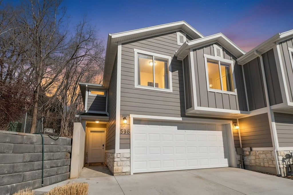 View of front of house with stone siding, a garage, board and batten siding, and driveway