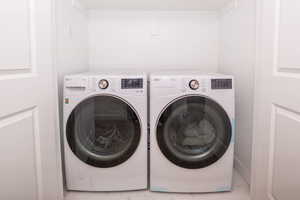 Laundry area with washer and clothes dryer and light marble finish flooring