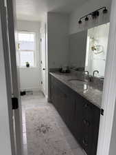 Bathroom featuring a textured ceiling, vanity, and light tile patterned floors