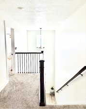 Hallway featuring light carpet and a textured ceiling