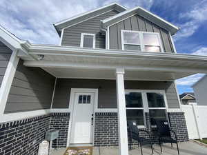 Property entrance featuring covered porch, brick siding, and board and batten siding