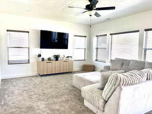 Carpeted living area with a ceiling fan and a textured ceiling