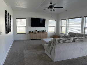 Carpeted living area featuring a textured ceiling and a ceiling fan