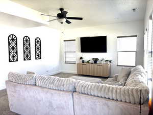 Living area with carpet floors, a textured ceiling, and ceiling fan