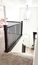 Stairs with carpet flooring and a textured ceiling