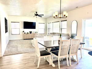 Dining area with a chandelier, a ceiling fan, light wood-style floors, and a textured ceiling