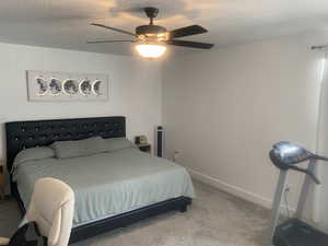 Bedroom featuring a textured ceiling, light carpet, and ceiling fan