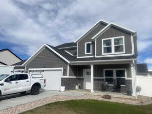 View of front of property with brick siding, a porch, board and batten siding, an attached garage, and concrete driveway