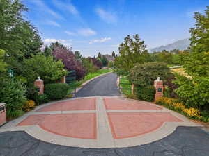 View of asphalt street featuring a gate and view of scattered trees