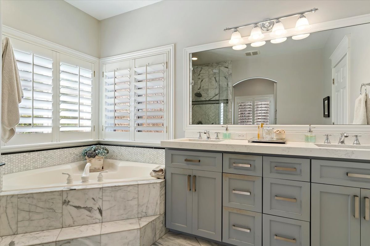 Bathroom with double vanity, a marble finish shower, and a bath