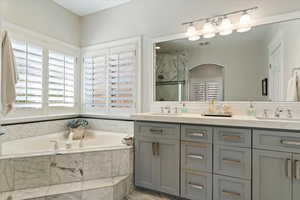 Bathroom with double vanity, a marble finish shower, and a bath