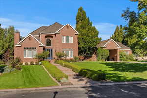 Traditional-style house featuring brick siding, a front yard, and a chimney