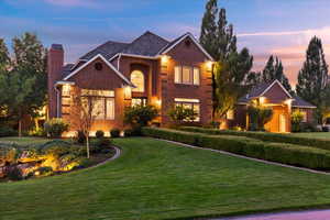 Traditional-style home with a front lawn, a chimney, and brick siding
