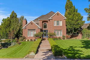 Traditional-style home with a front yard, brick siding, and a chimney