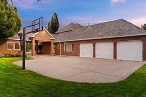 View of front of home with a yard, brick siding, concrete driveway, and a garage