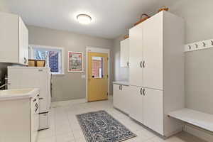 Mudroom with washer / clothes dryer and light tile patterned flooring