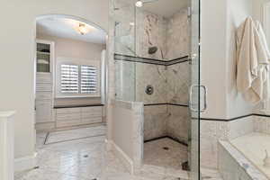 Bathroom featuring a marble finish shower, a bath, and light marble finish flooring