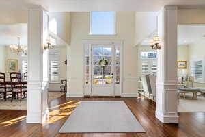 Foyer with ornate columns, suspended lighting, healthy amount of natural light, and a high ceiling