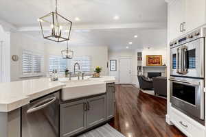 Kitchen with stainless steel appliances, light stone counters, open floor plan, a fireplace, and dark wood-style floors
