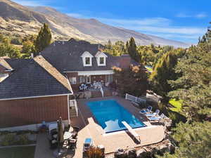 Back of property with a patio area, a fenced backyard, brick siding, an outdoor pool, and a mountain view