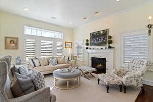 Living room featuring ornamental molding, a tile fireplace, and recessed lighting
