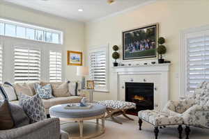 Carpeted living area featuring crown molding, a tiled fireplace, and recessed lighting
