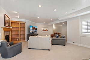Living room featuring a high end fireplace, ornamental molding, light colored carpet, a textured ceiling, and recessed lighting