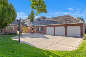 View of side of property featuring a yard, a garage, concrete driveway, and brick siding