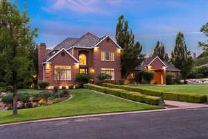 View of front of house featuring a yard, a chimney, and brick siding