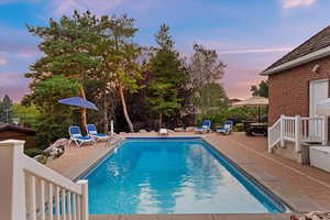 Pool at dusk with a patio and an outdoor pool
