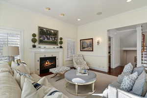 Living area featuring crown molding, a tile fireplace, wood finished floors, and recessed lighting