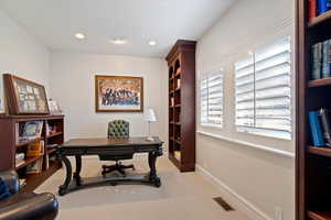 Office space with light carpet and recessed lighting