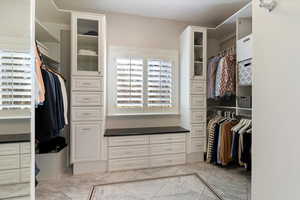 Walk in closet featuring light marble finish flooring