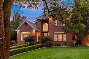 Traditional-style house with a lawn, brick siding, and a chimney