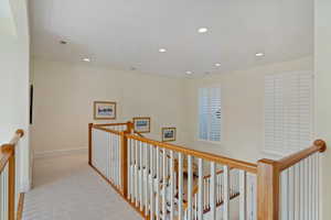 Corridor with light colored carpet, an upstairs landing, and recessed lighting