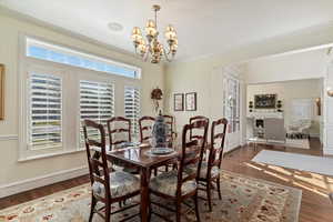 Dining area featuring suspended lighting, dark wood-style flooring, and ornamental molding