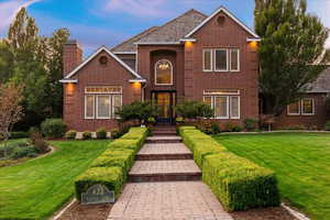 Traditional-style home with a front lawn, brick siding, and a chimney