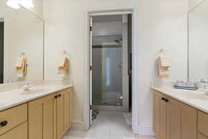 Bathroom with two vanities, a shower stall, and light tile patterned floors