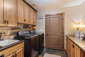 Laundry area with cabinet space, washer and clothes dryer, and dark stone finish floors