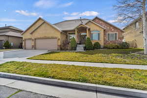 View of front of home with a garage, driveway, a front yard, stucco siding, and a shingled roof