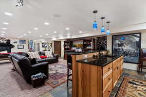 Bar area with dark stone countertops, stone tile flooring, and decorative light fixtures