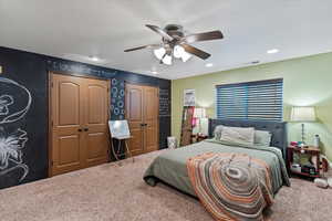 Carpeted bedroom featuring multiple closets, ceiling fan, and recessed lighting