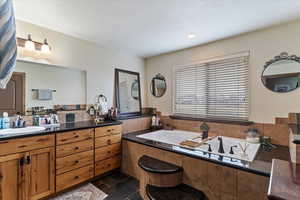 Full bath with vanity, a bath, and stone tile floors