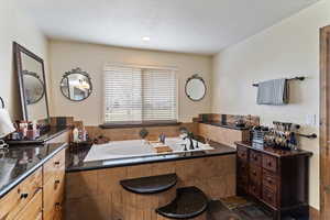 Bathroom featuring a garden tub and dark stone finish floors